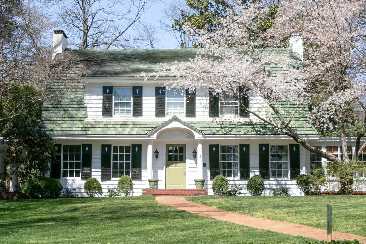 A white house with a green roof and black shutters.