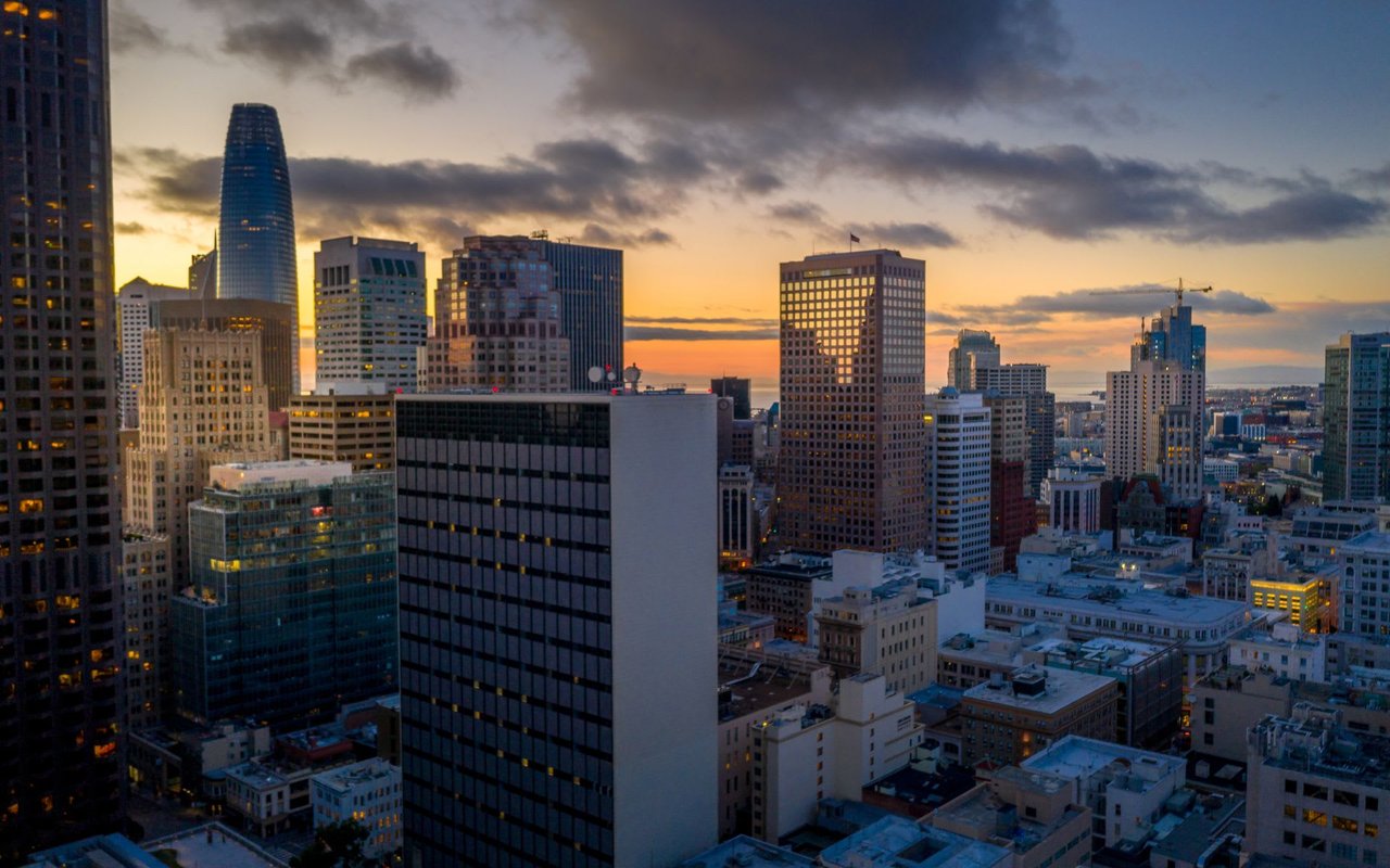 an aerial view above Nob Hill in San Francisco Dramatic sunrise sky with light shining on the skyscrapers glass windows. Looking to the San Francisco Bay.