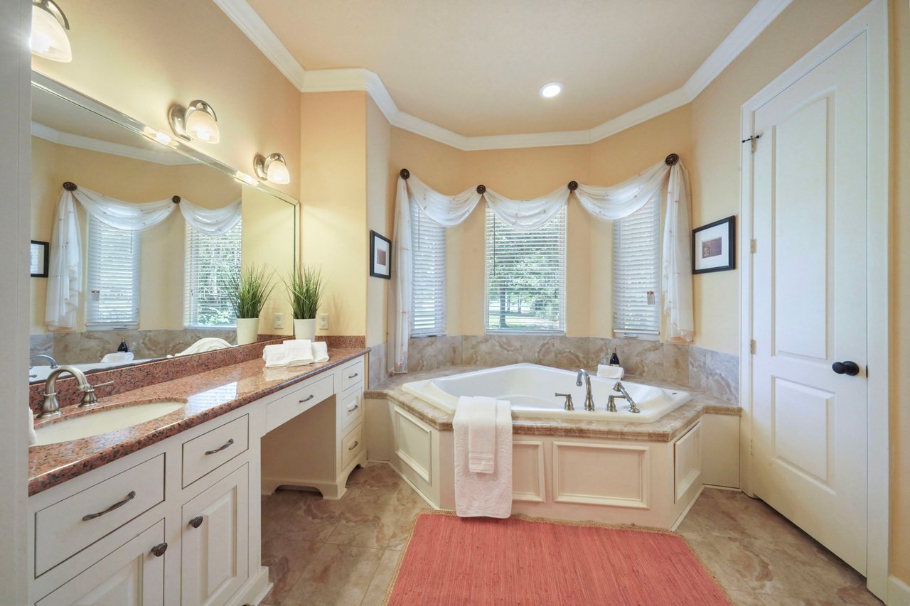 Primary ensuite bath has two separate vanities with granite counters. The Jetted tub is tucked into the bay window for natural light and view to lake.