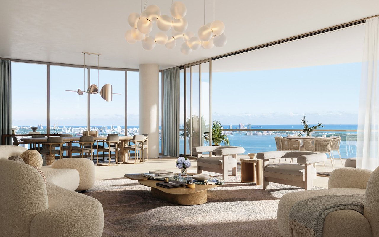 Luxury living and dining room with floor-to-ceiling windows overlooking Miami’s skyline and waterfront.
