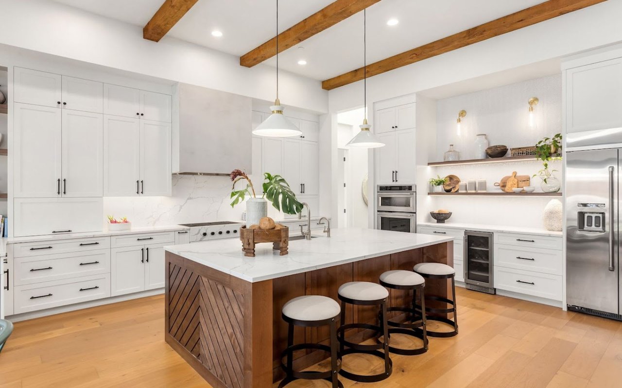 A luxury home feeaturing a kitchen with a large island and stools. 