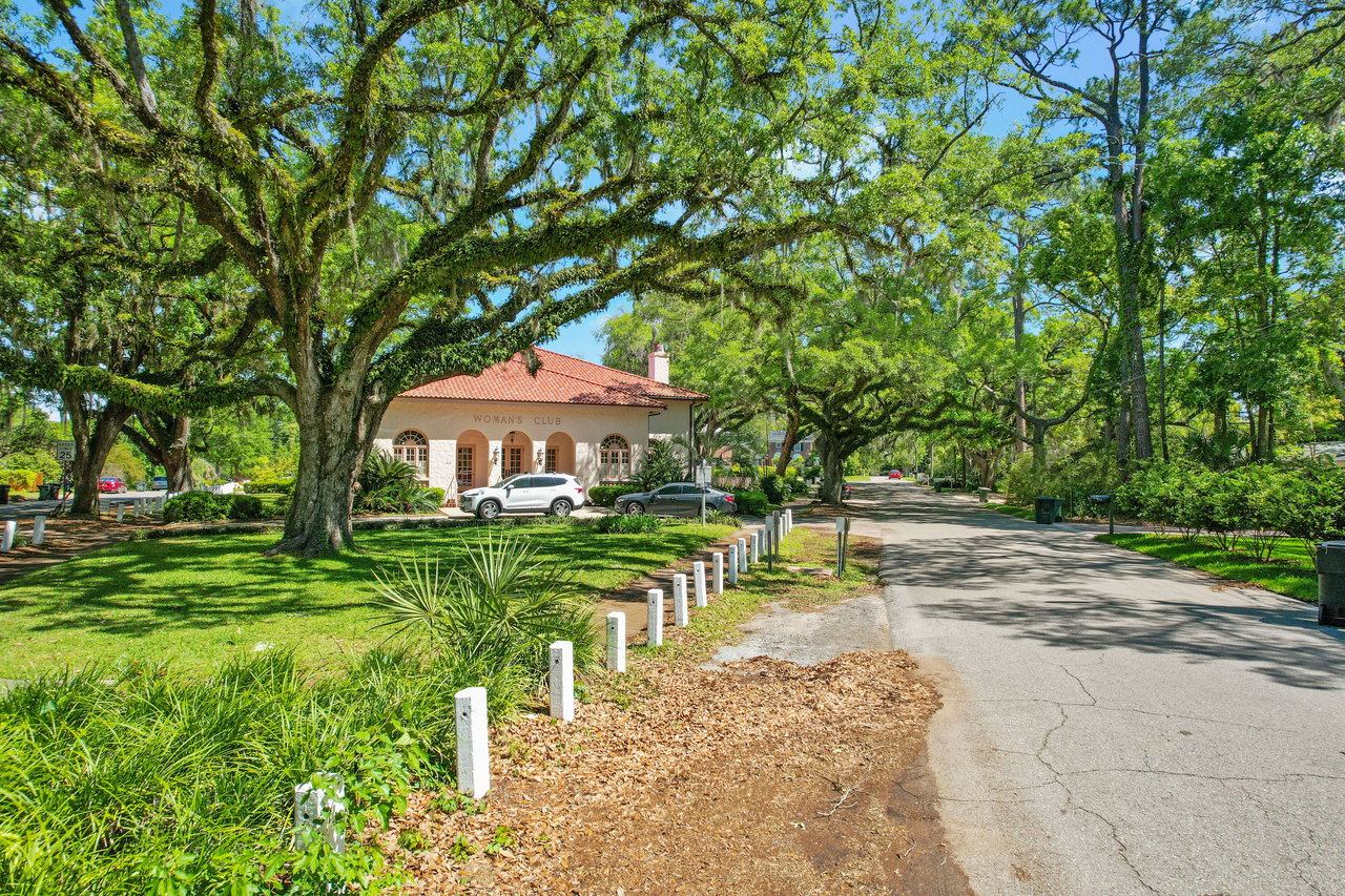 A ground-level view of a scenic area within the Los Robles neighborhood, featuring a large tree, pathway, and a historic-looking house.