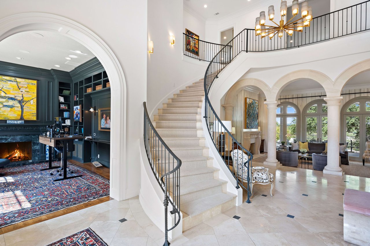 Upon entering the grand foyer, one is immediately greeted by a stately office on one side and a sophisticated formal dining area on the other. Exuding opulence and elegance, the central highlight of this space is the stunning staircase adorned with wrought iron railings that epitomize luxury and craftsmanship. Every detail in this estate, from its bespoke furnishings to its meticulously curated decor, resonates with the pinnacle of upscale living.