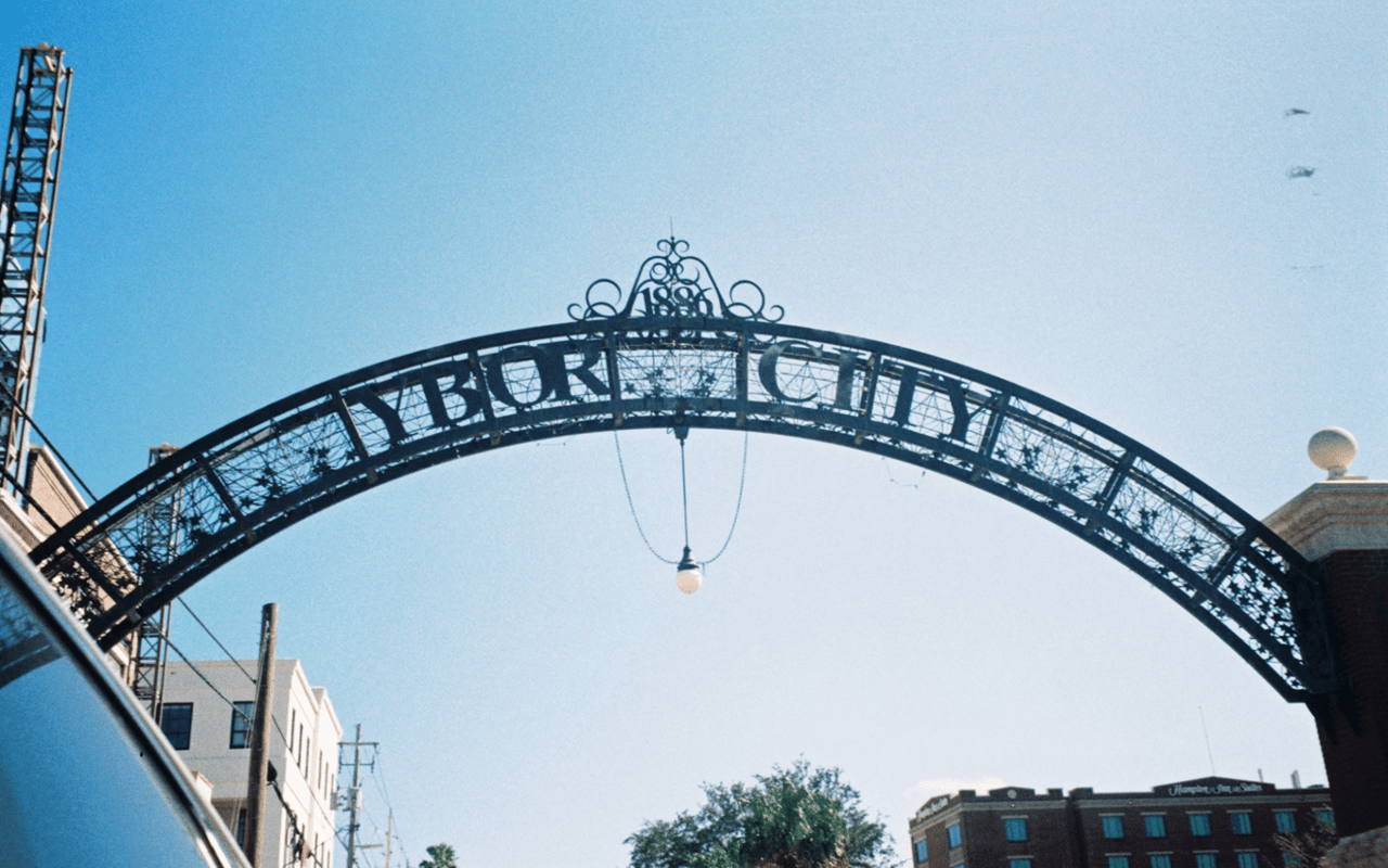 An ornate, dark metal archway with the words "YBOR CITY" prominently displayed across its top. 