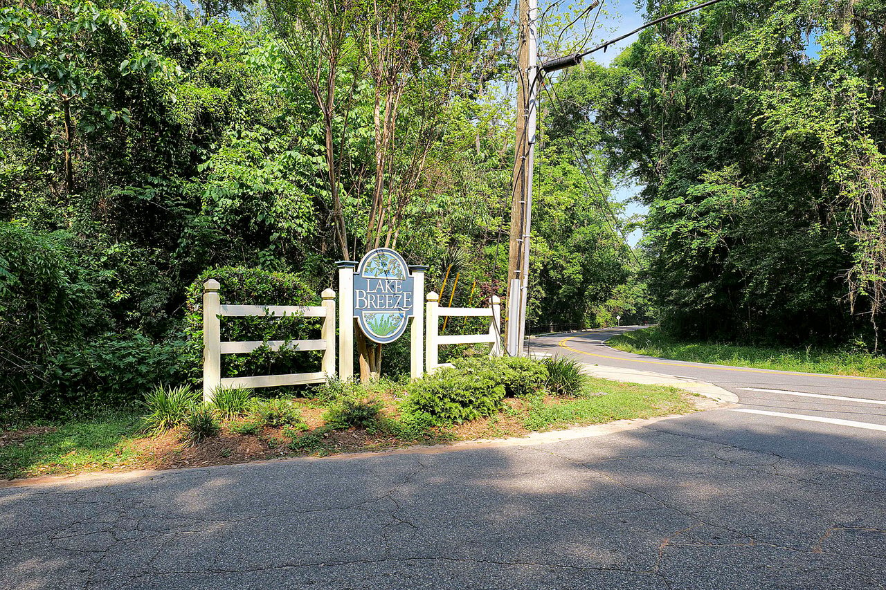 A view of a gated entrance to the Lake Breeze community, featuring lush greenery and a welcoming entrance sign.