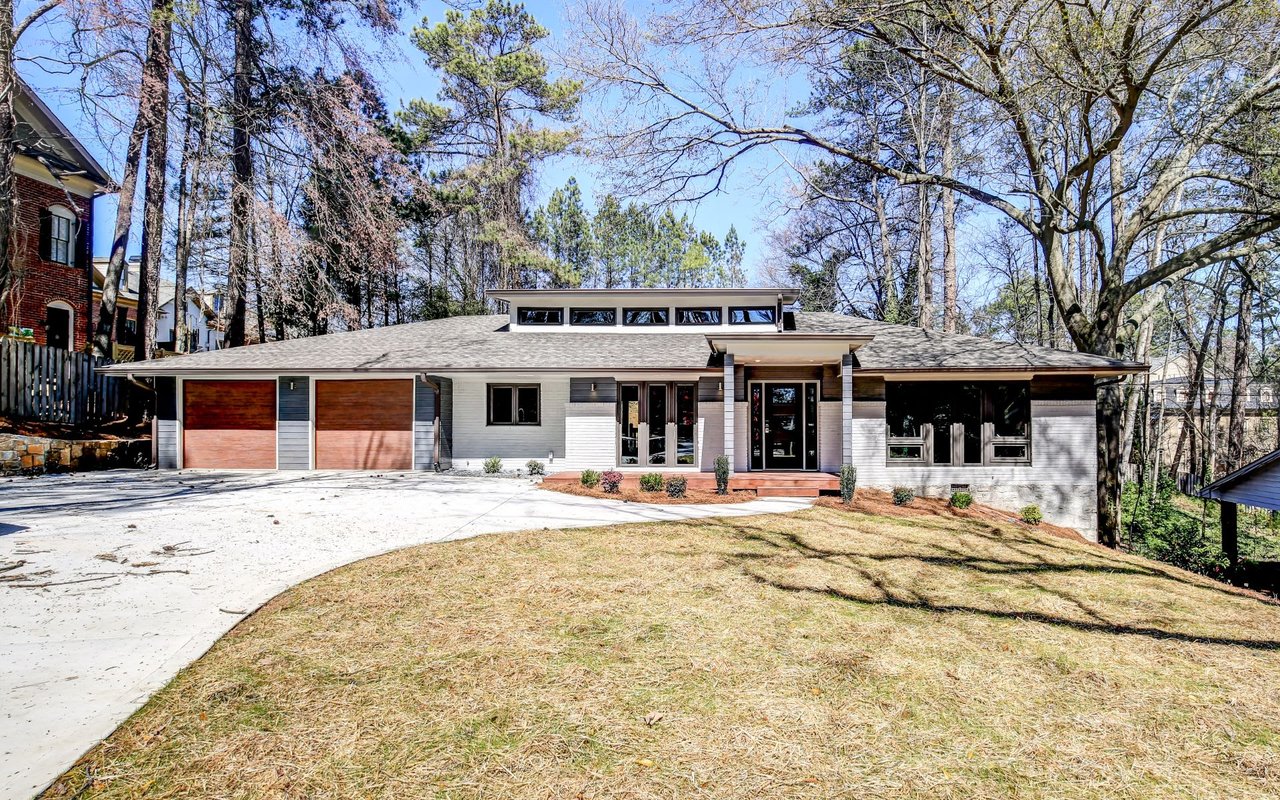 Single-family white house with gray roof, porch, 2-car garage, paved driveway, and front yard.