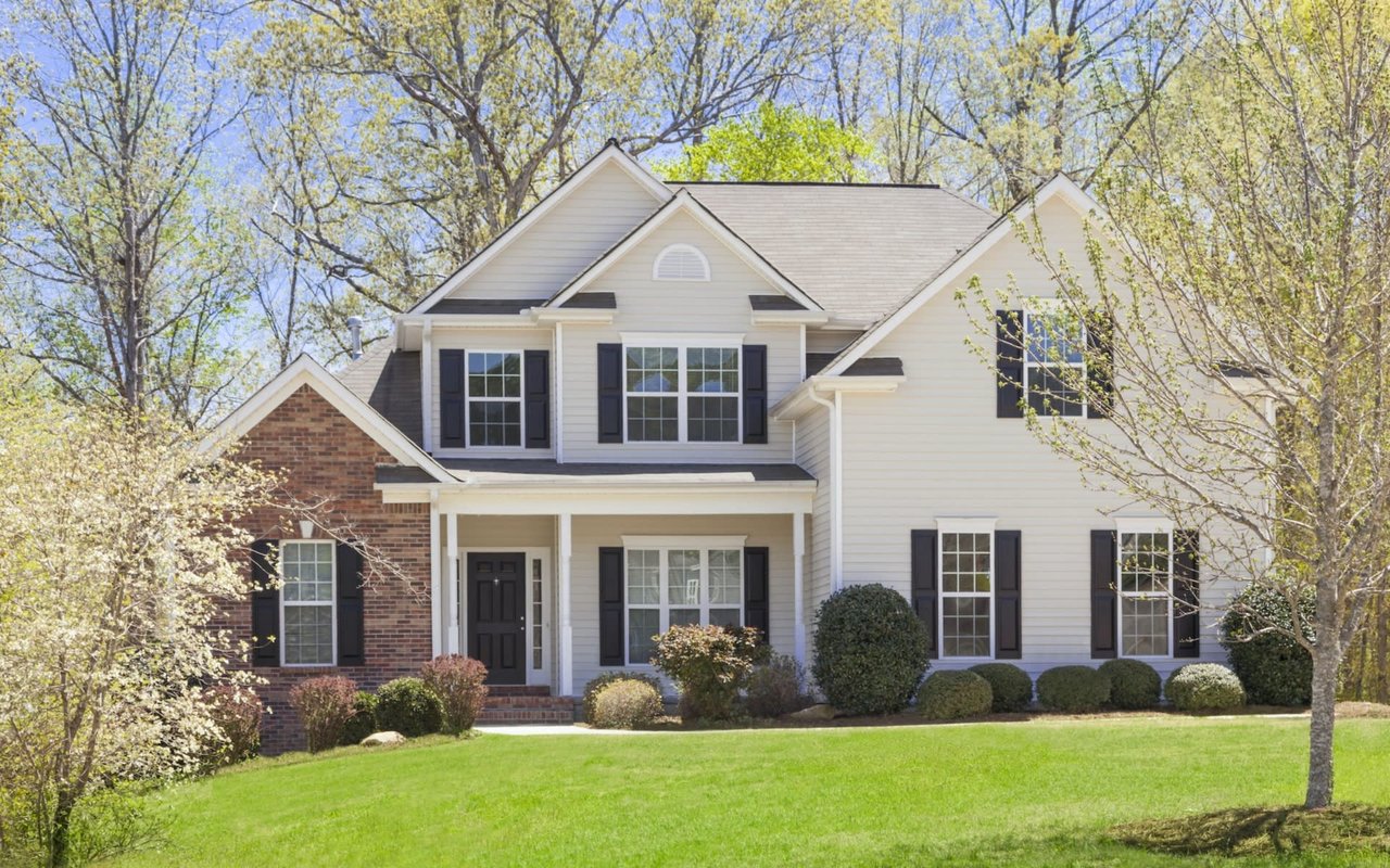 A white house with black shutters on a sunny day.