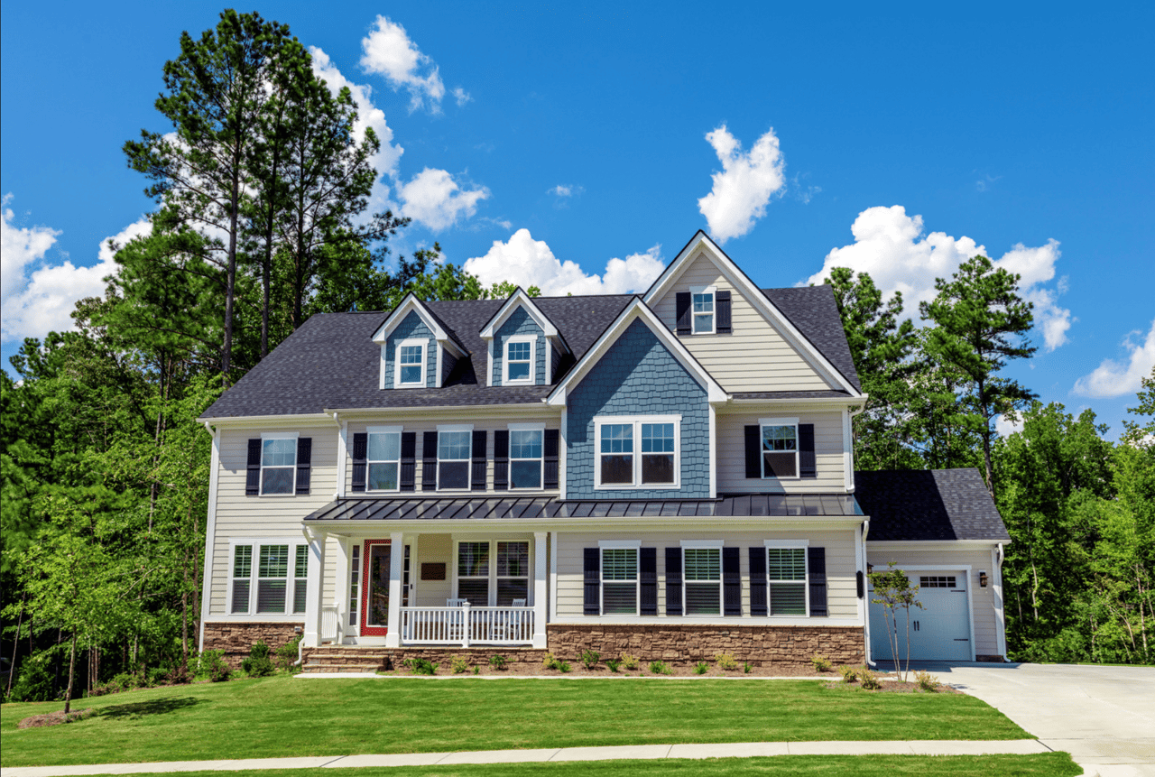 A large colonial style house with a gray shingled roof and many windows.