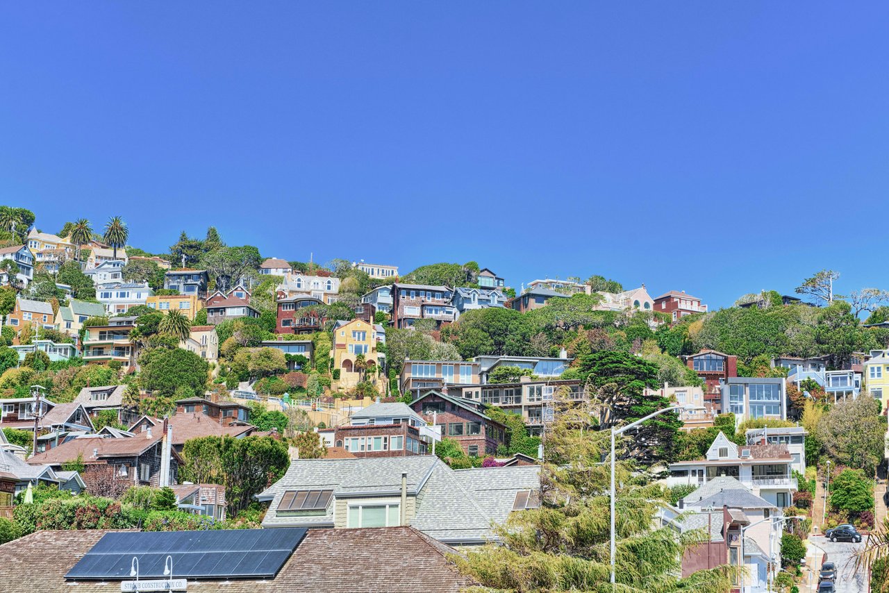 A row of colorful houses in different sizes sits on a hilltop.