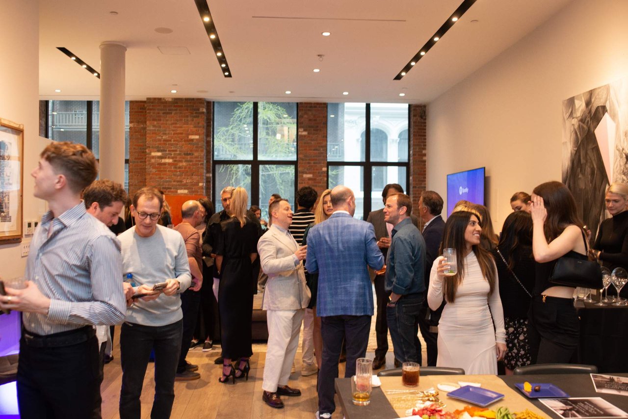 Guests mingle at a networking event in a modern brick-walled venue.
