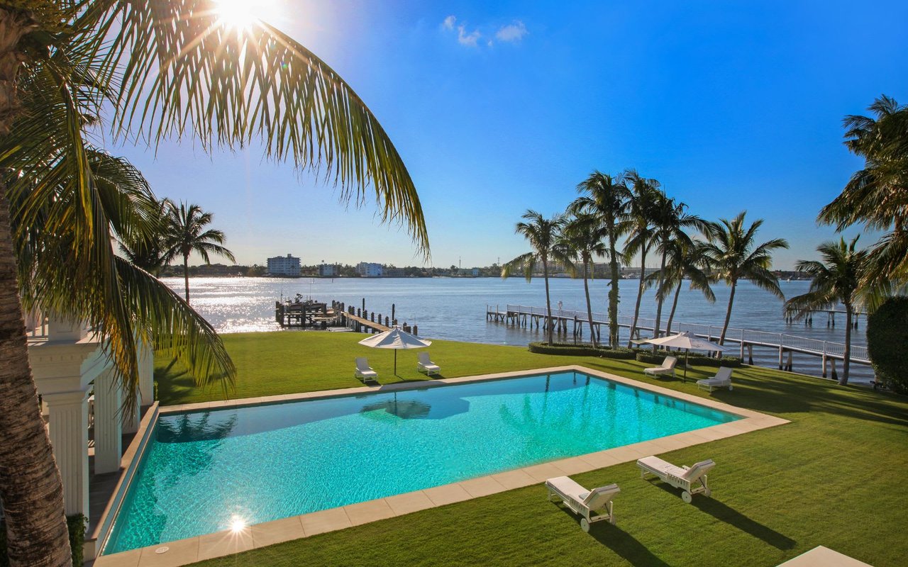 A large swimming pool surrounded by palm trees and a dock