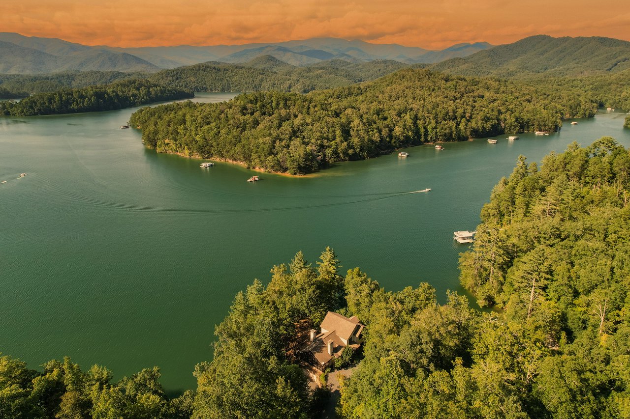 Alt=The drone view of Fontana Lake in western NC highlights blue waters, lush forests, Smoky Mountains.