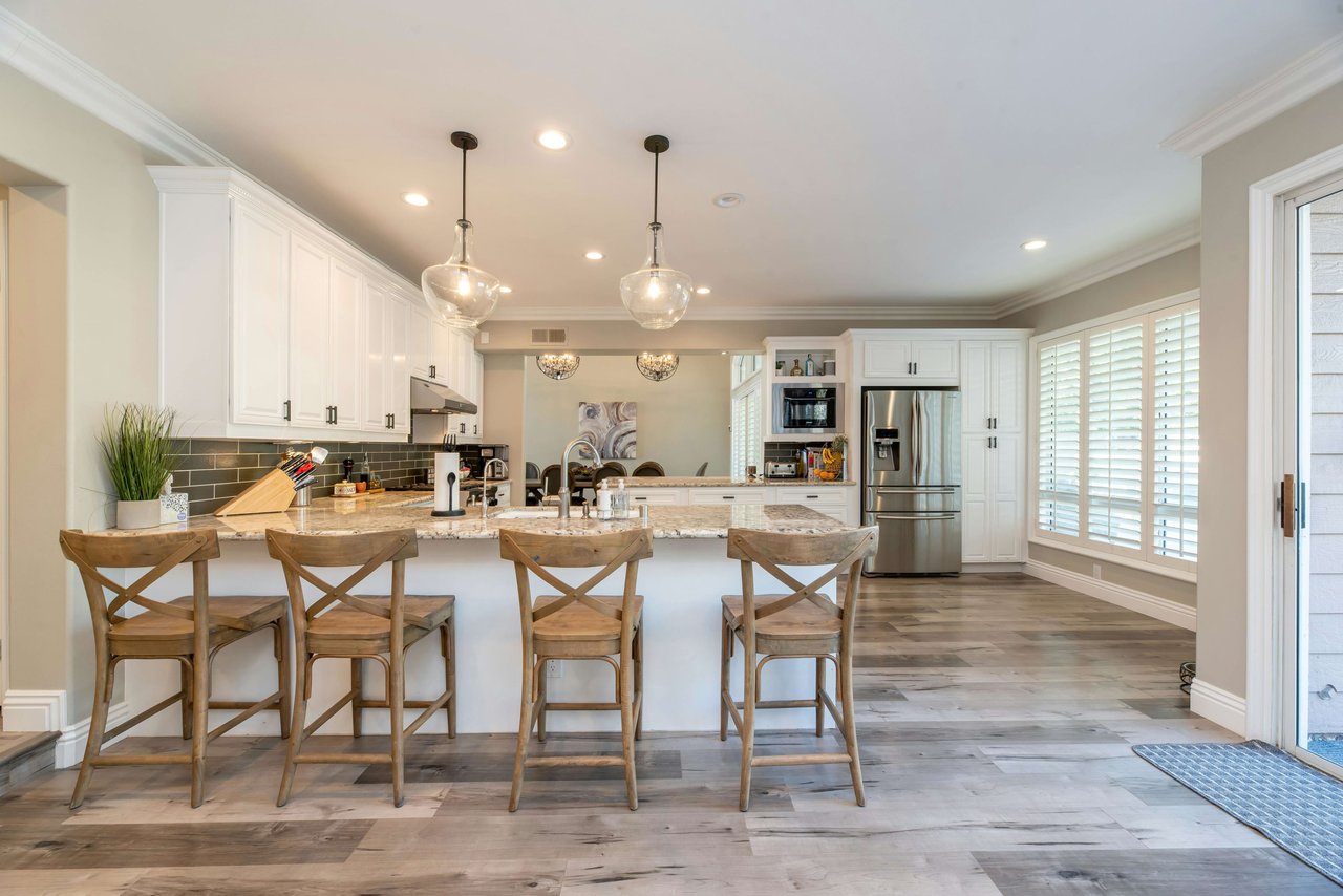 Bright, modern kitchen with white cabinets, granite countertops, and stainless steel appliances.