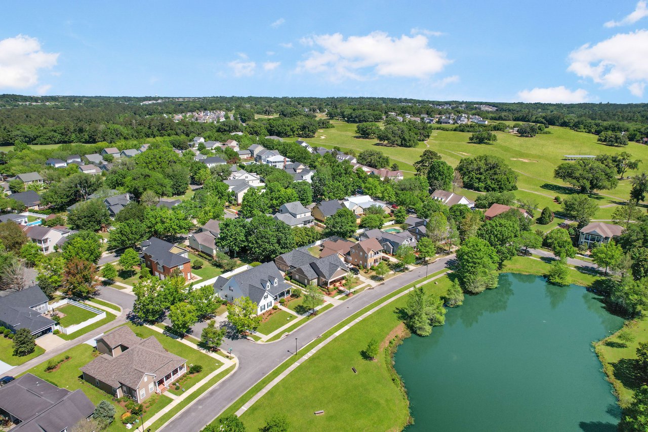 An aerial view of a residential area in Southwood with houses and a pond, surrounded by green spaces.