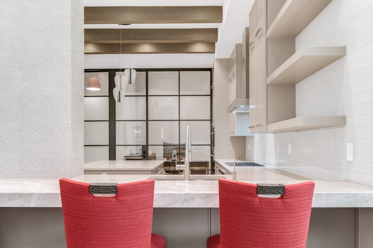 Open-concept space capturing a stylish kitchen framed by two striking red stools, creating a vibrant and inviting atmosphere.