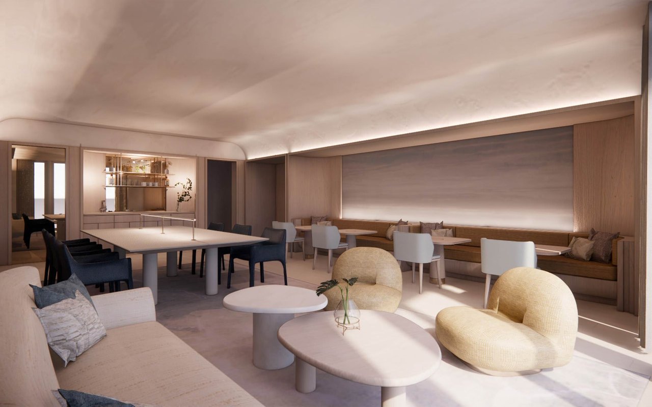 Furnished lounge and dining area with a long table, built-in seating, and rounded chairs.