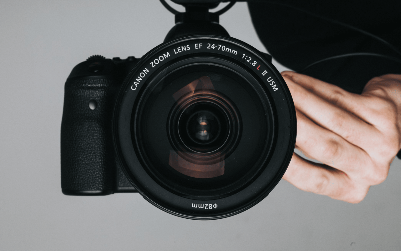  A close-up, top-down view of a black Canon DSLR camera with a large lens facing directly upwards.