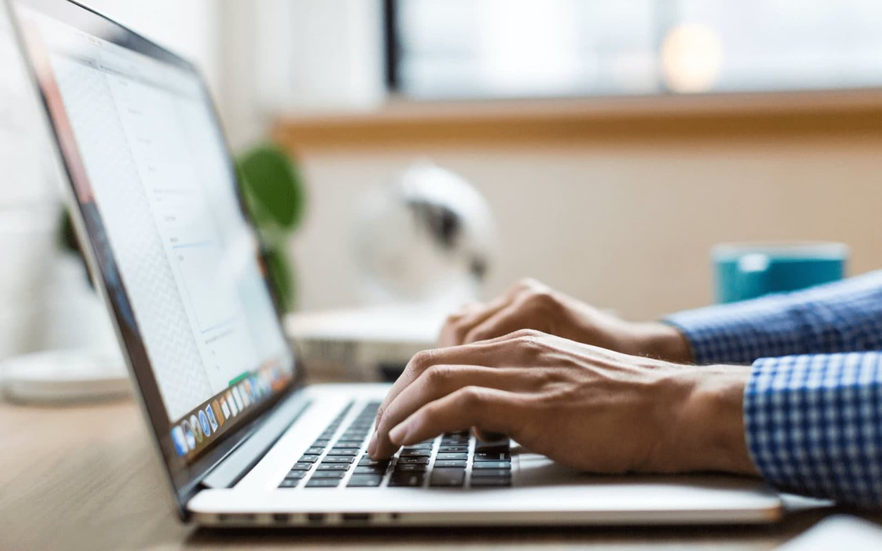 Hands typing on a laptop at a desk.