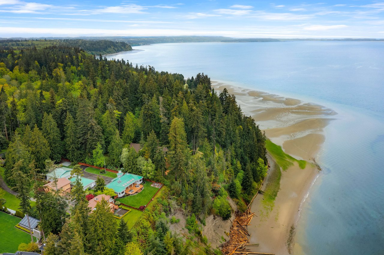 An aerial view of a coastal property with a house nestled amidst lush green trees