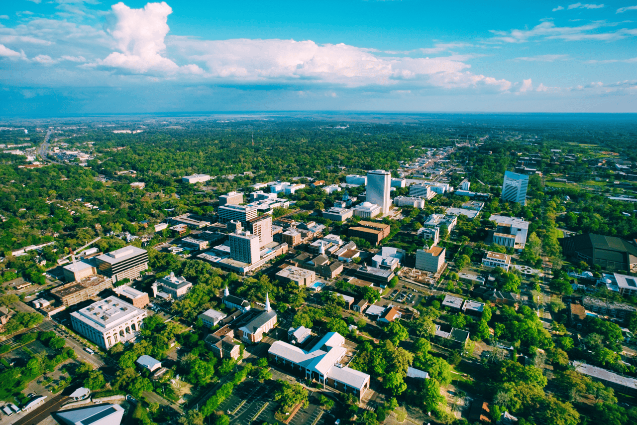 An aerial photograph of a cityscape, showing a large urban area with buildings, roads, and greenery.