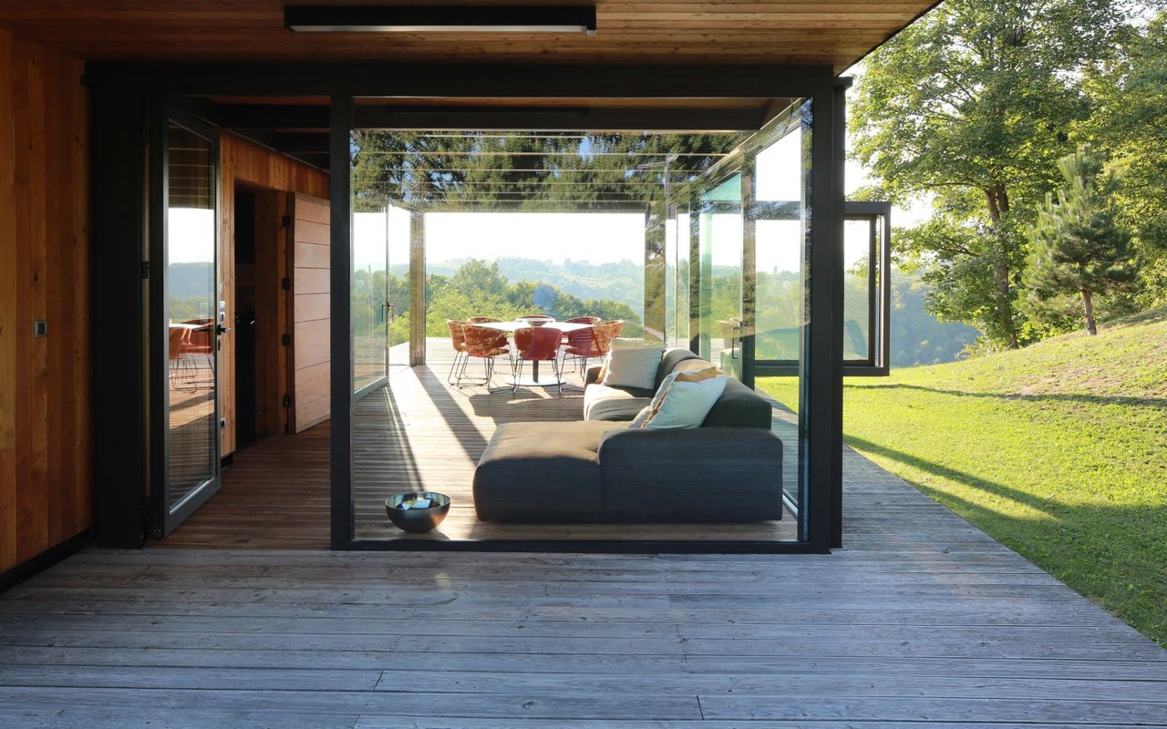 a couch sitting on top of a wooden deck with a round table with red chairs