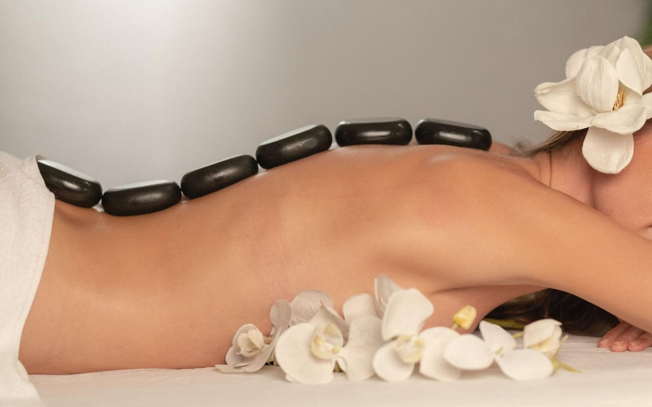 A close-up shot of a person lying on their stomach, receiving a hot stone massage.