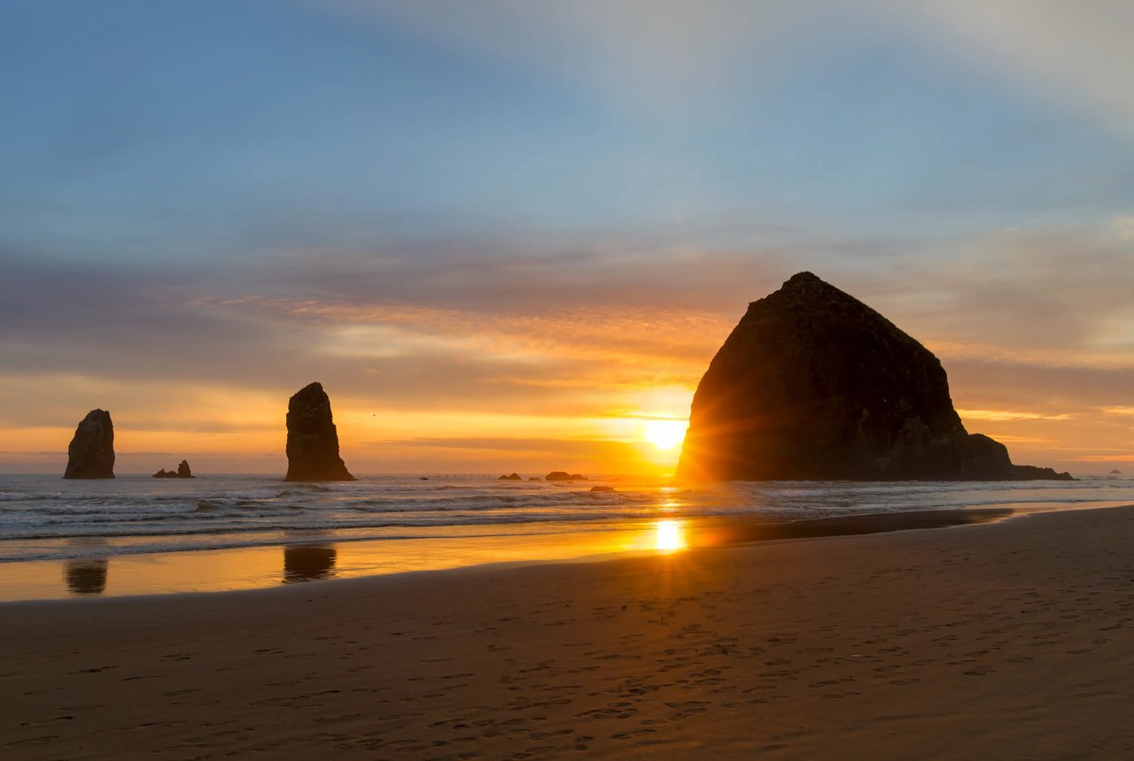 The seun set peeking around haystack rock in Cannon Beach