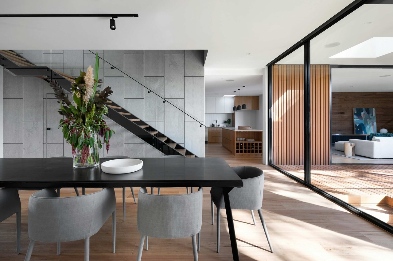 Modern dining room and living area showcasing clean lines, minimalist design, and natural materials such as wood and stone, creating a warm yet contemporary atmosphere.