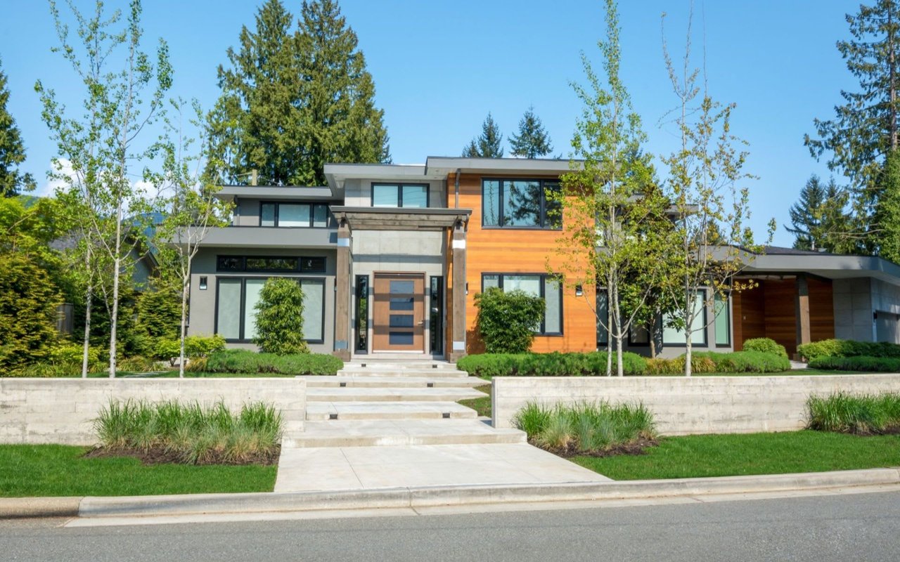 The house has multiple levels and large, dark-framed windows. 