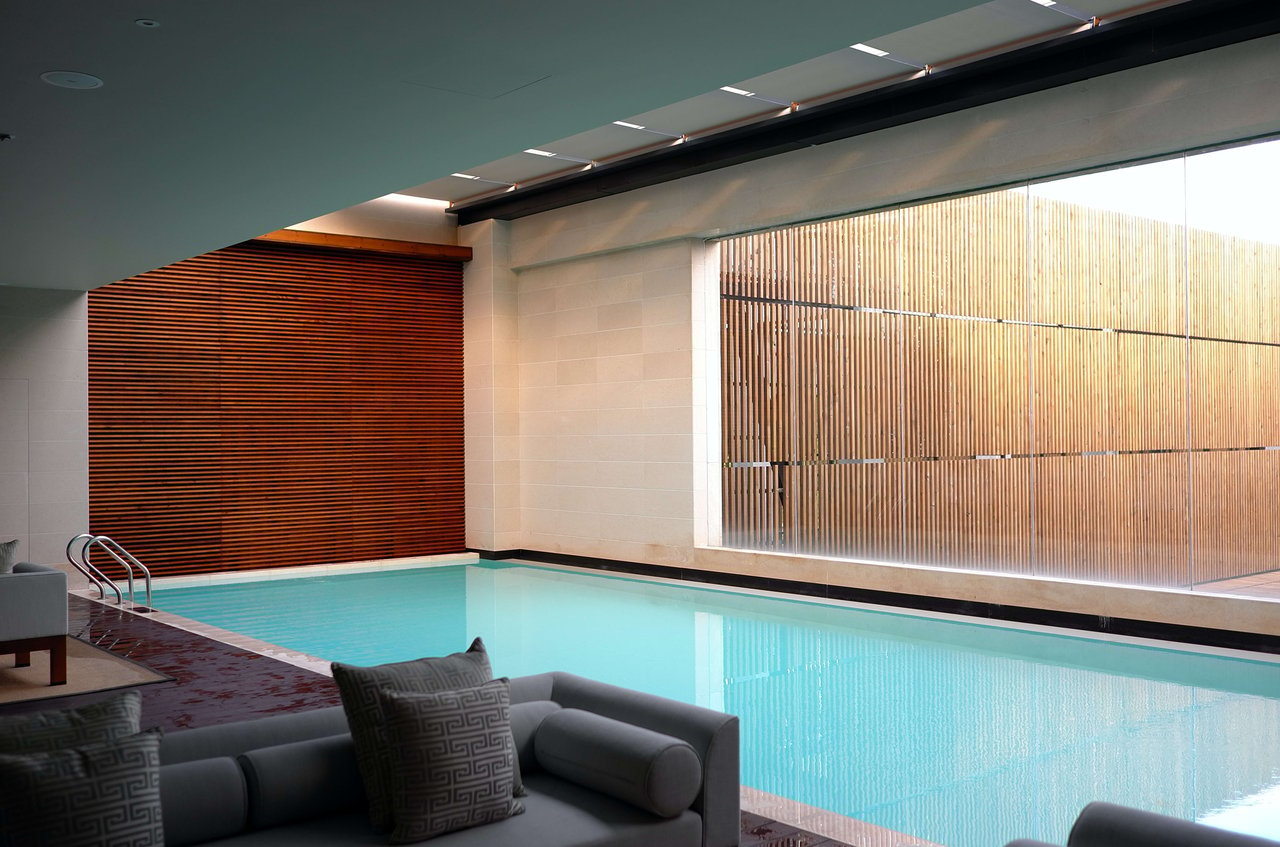 A large indoor swimming pool with a couch and pillows in front of it.