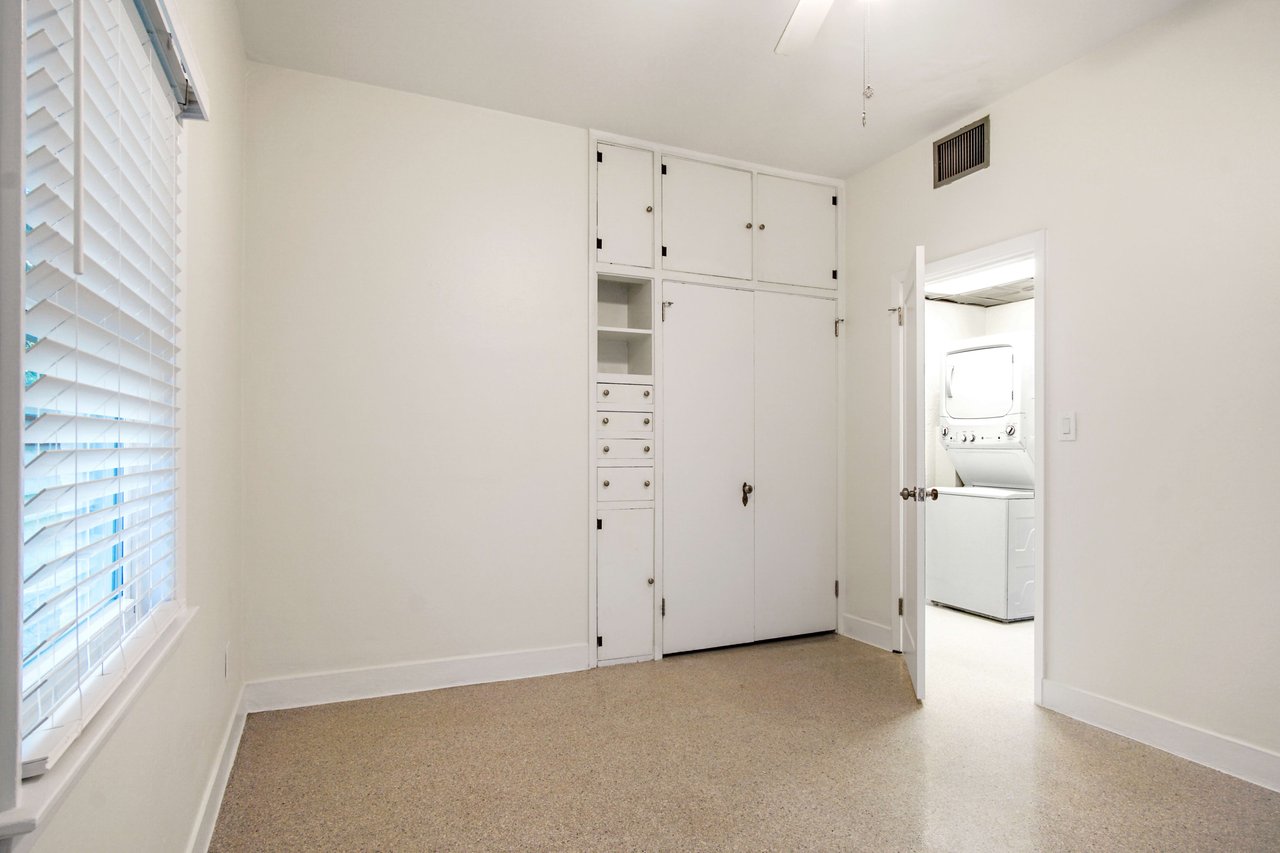 A view of the third bedroom, highlighting additional built-in storage and a large window.