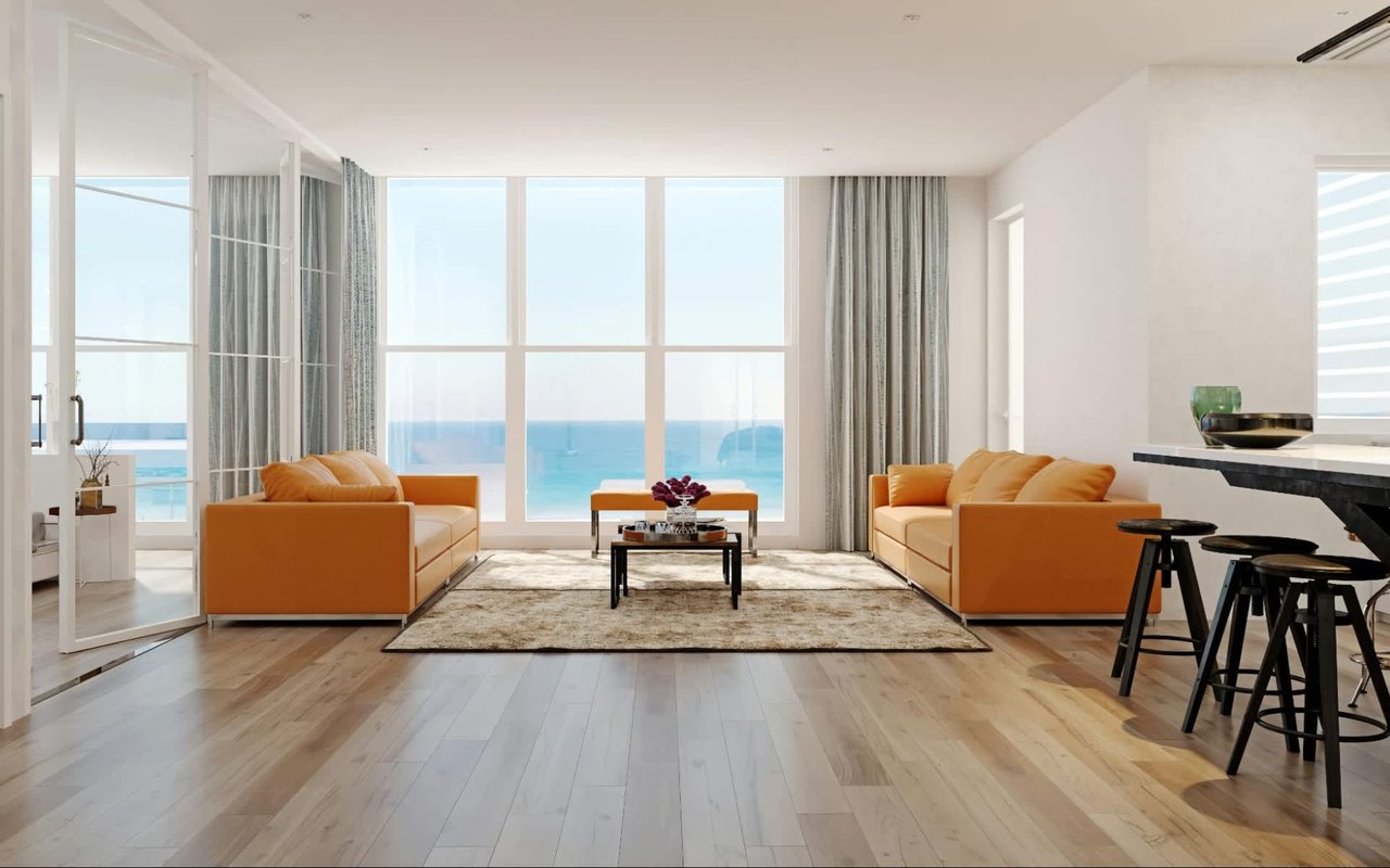 Living room with orange couches, wood flooring,  and modern design. Waterfront floor to ceiling windows overlooking the intracoastal and blue ocean.