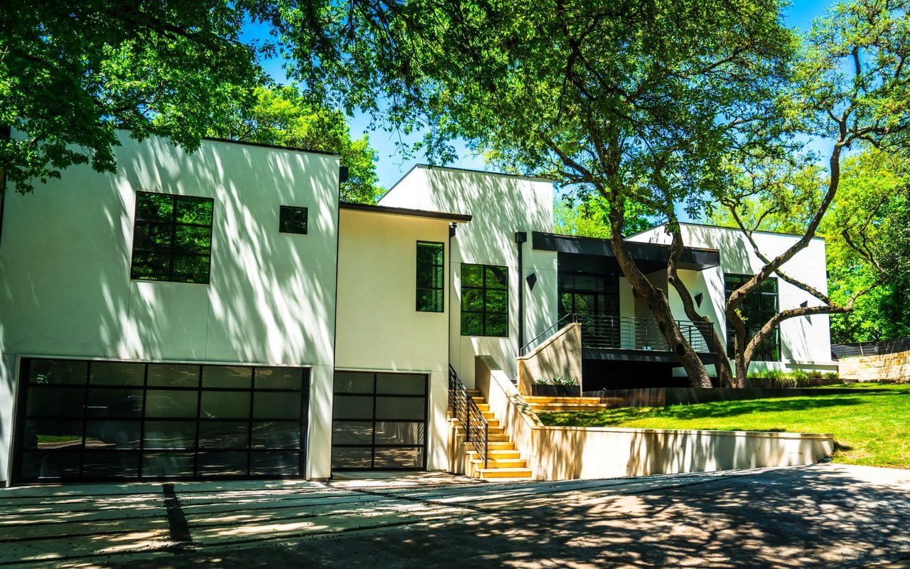 A modern white house with a glass garage door and a black frame.