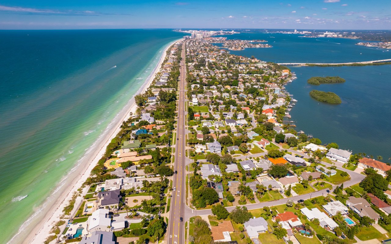 An aerial view of a neighborhood beside a long road and the sea.