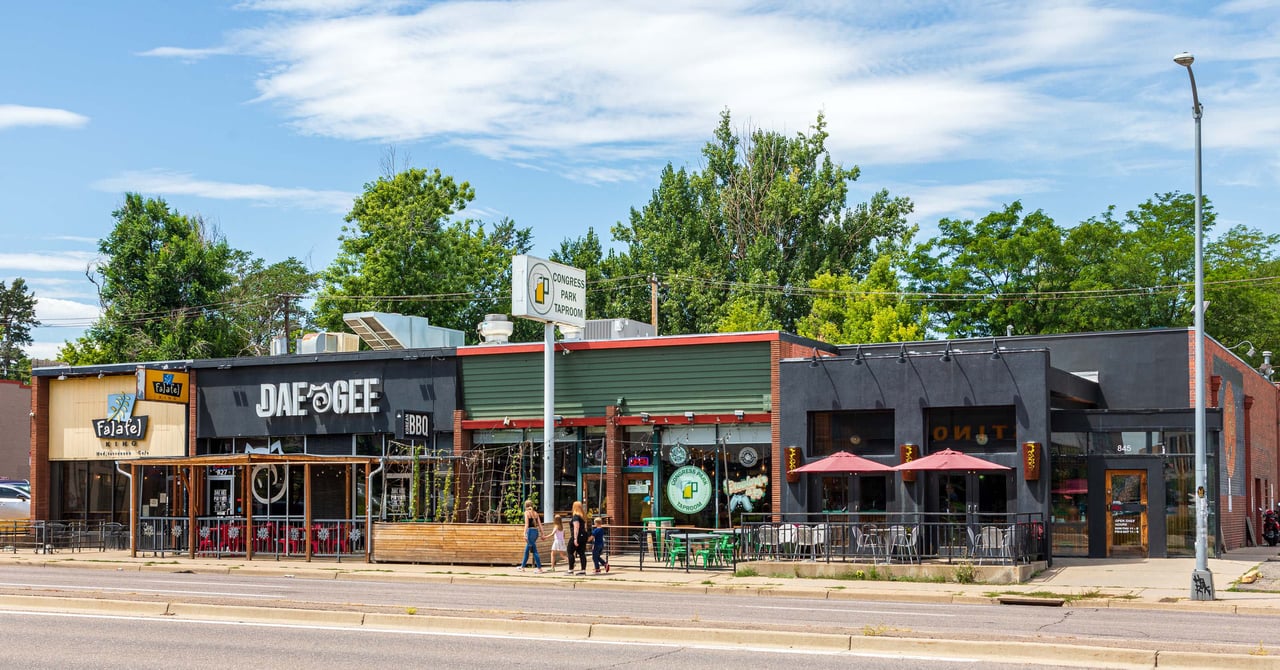 A row of outdoor restaurant tables with umbrellas on a city street