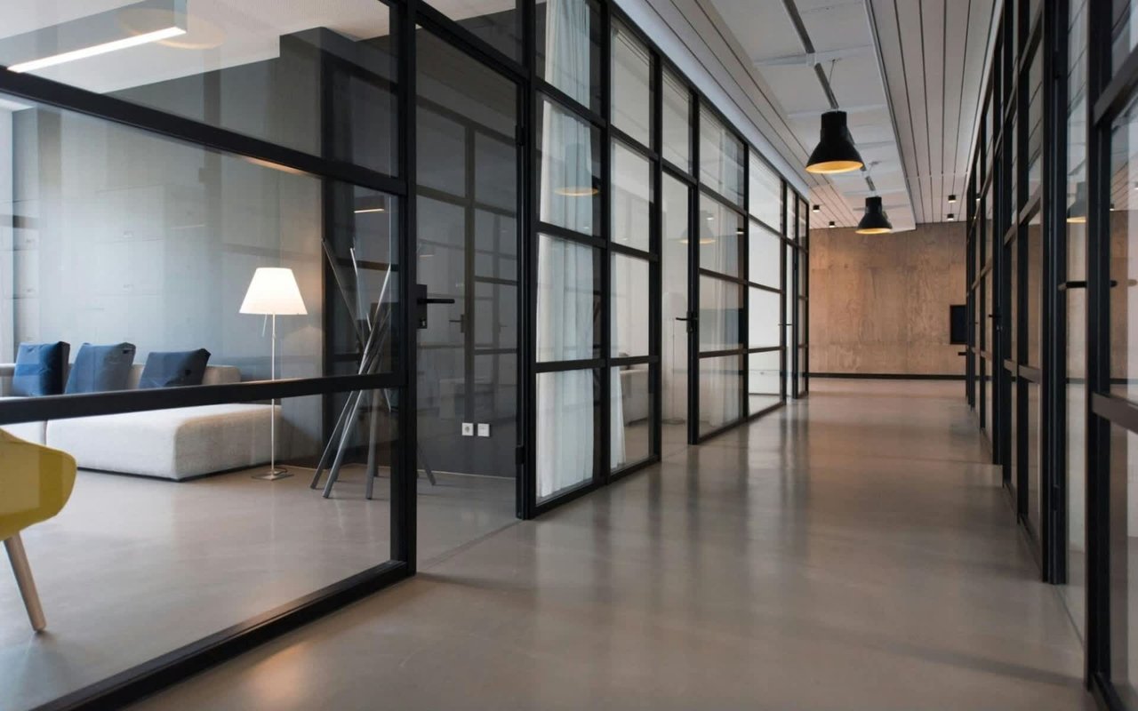  An interior view of a modern office space with a long, polished concrete floor hallway.