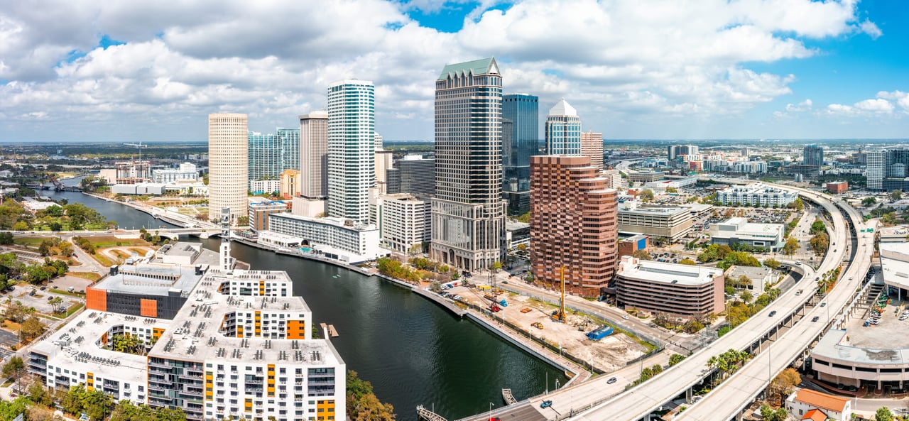 An aerial panoramic view of downtown Tampa, Florida, on a partly cloudy day.