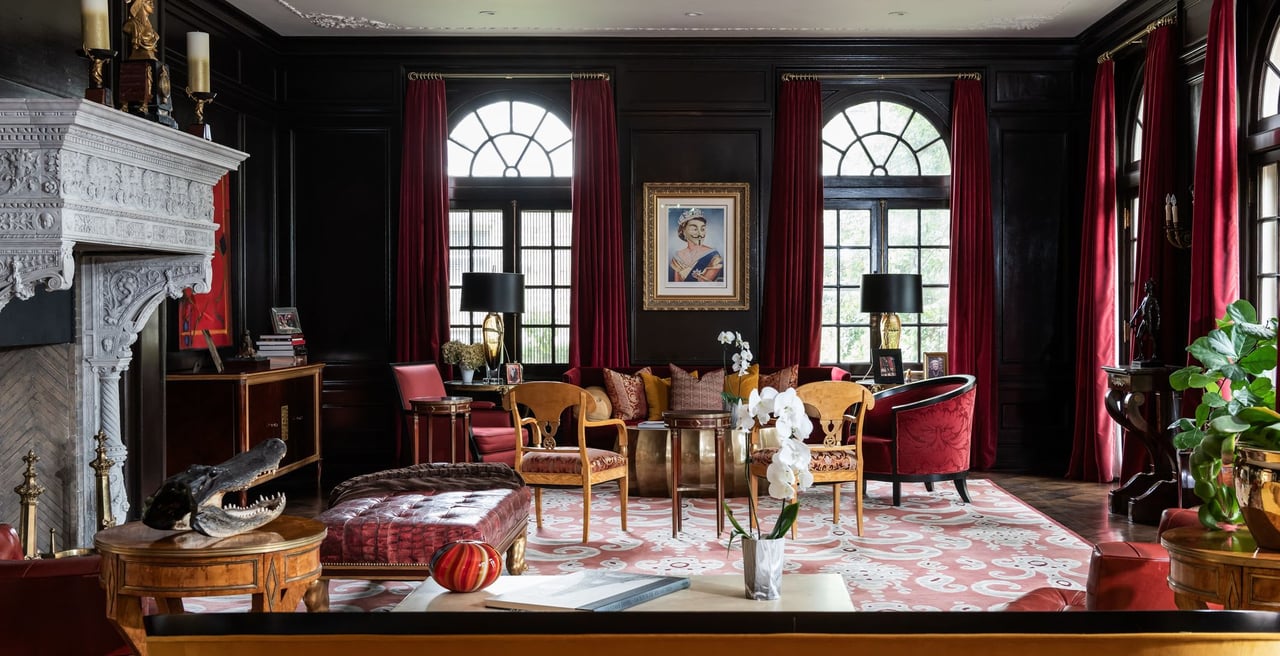 A living room with a fireplace, a couch, chairs, and a painting of a woman on the wall.