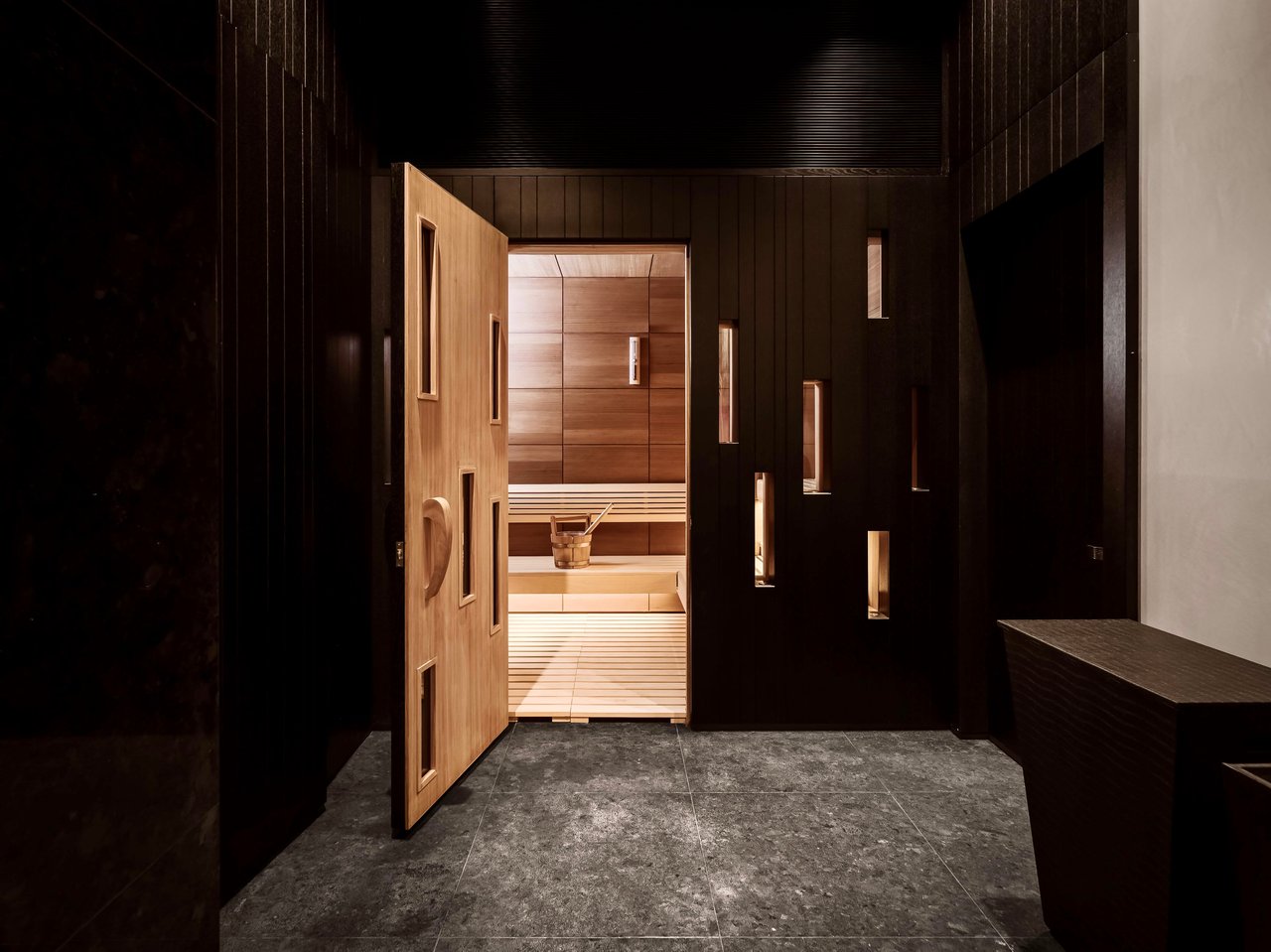 A partially open wooden door leading into a sauna