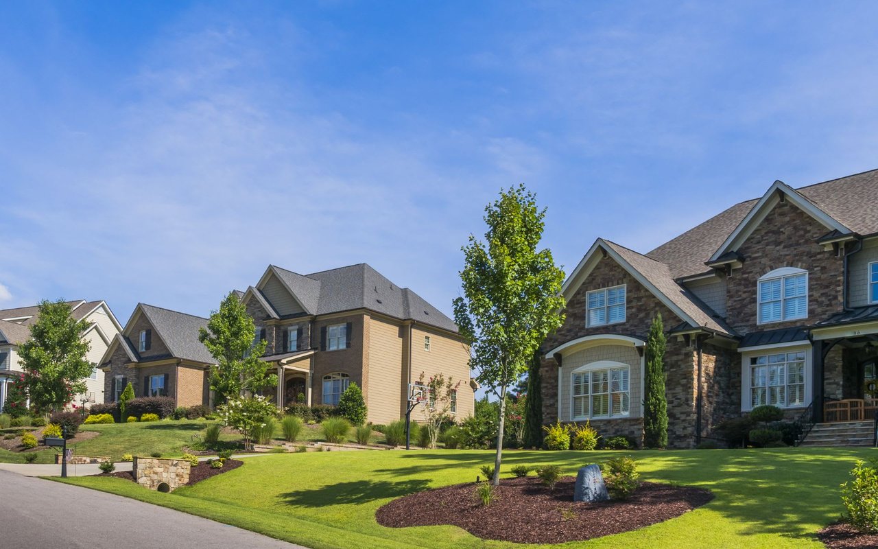 A two-story single-family home in a suburban neighborhood with a porch, garage, landscaped yard, and sidewalk.