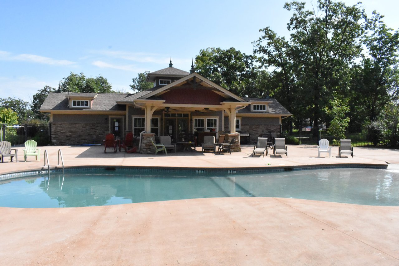 A community pool area with a large swimming pool, lounge chairs, and a gazebo