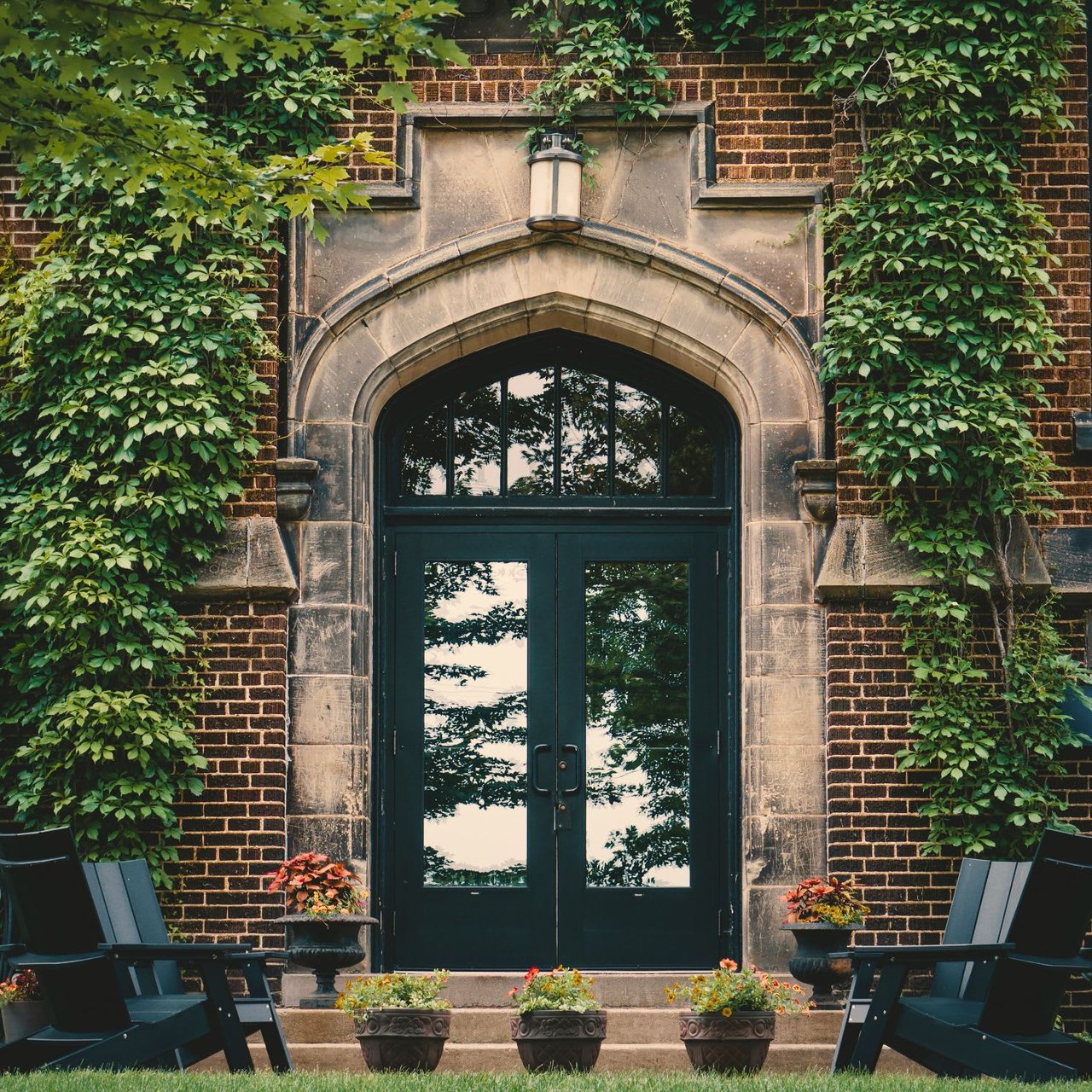  A detailed shot of an arched, dark double door set into a brick building, possibly an old church or institutional building. 