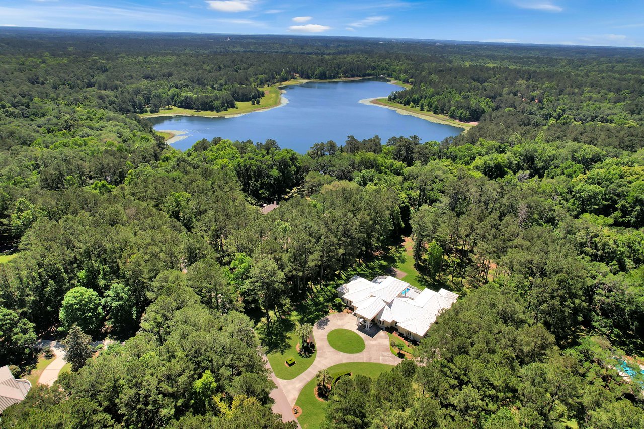 An aerial view of a residential area in Rosehill with a large body of water and houses surrounded by dense greenery.