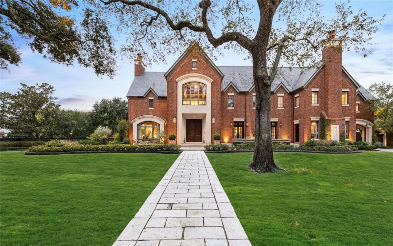 Majestic luxury estate with a grand brick facade, arched entryway, and an inviting path.