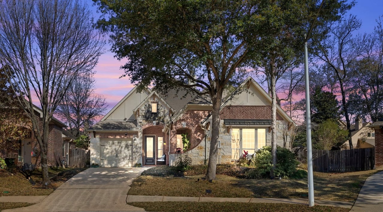 Lakewood Grove home with brick and stone exterior, single-car garage, and mature trees at dusk.