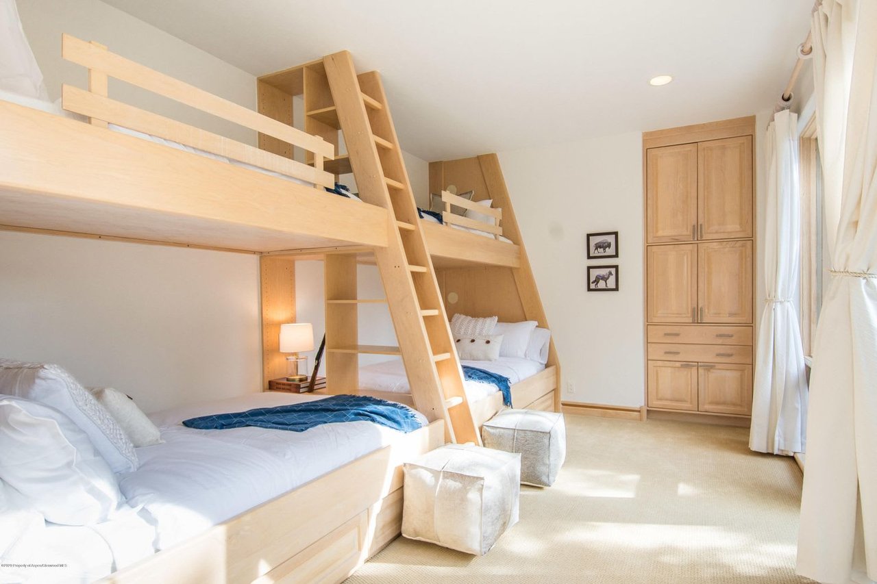 Bedroom with built-in light-wood bunk beds, ladders, and a matching wardrobe.