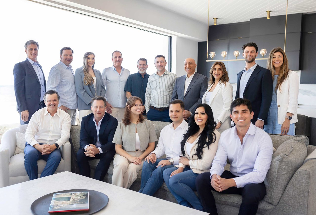 16 agents sat around a sofa at a luxury lisitng