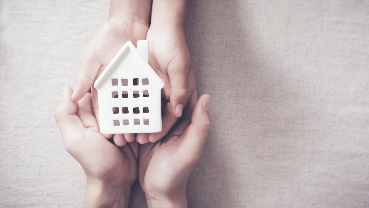 House held by a child and adult on their hands.