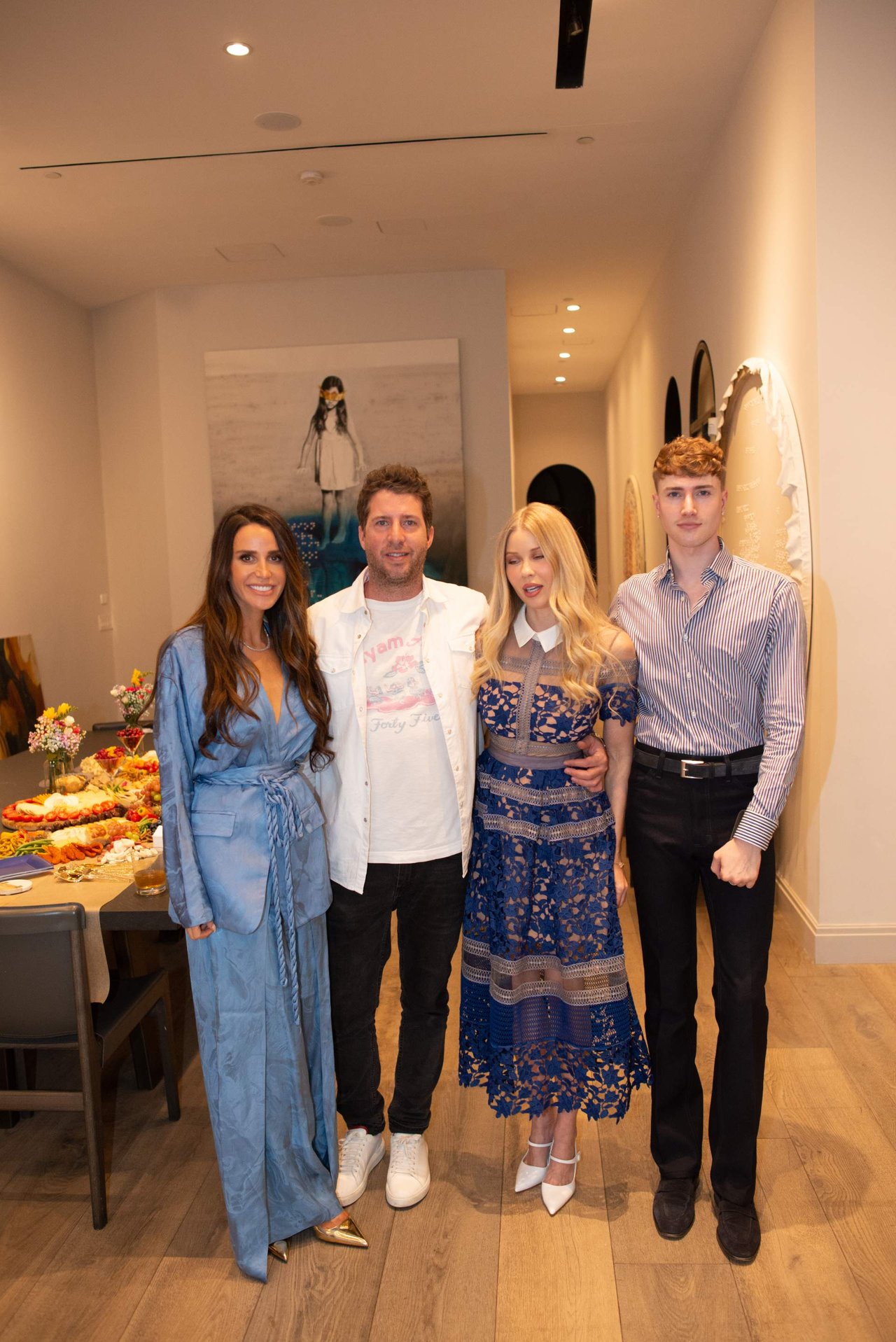 Four people pose together indoors beside a table of refreshments.
