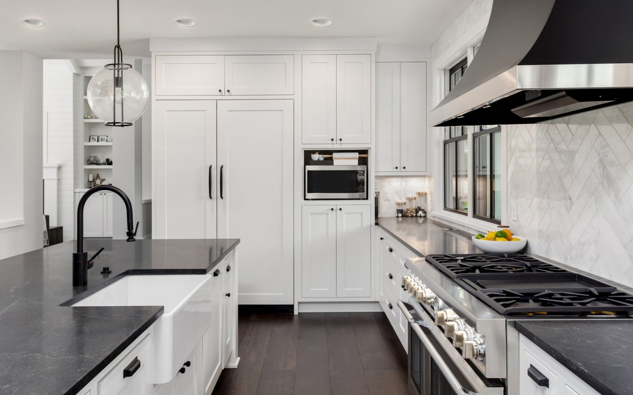  A modern kitchen features dark countertops and white cabinetry